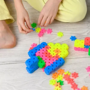 Niño jugando en el suelo con bloques de construcción Meli de colores para trabajar la motricidad fina